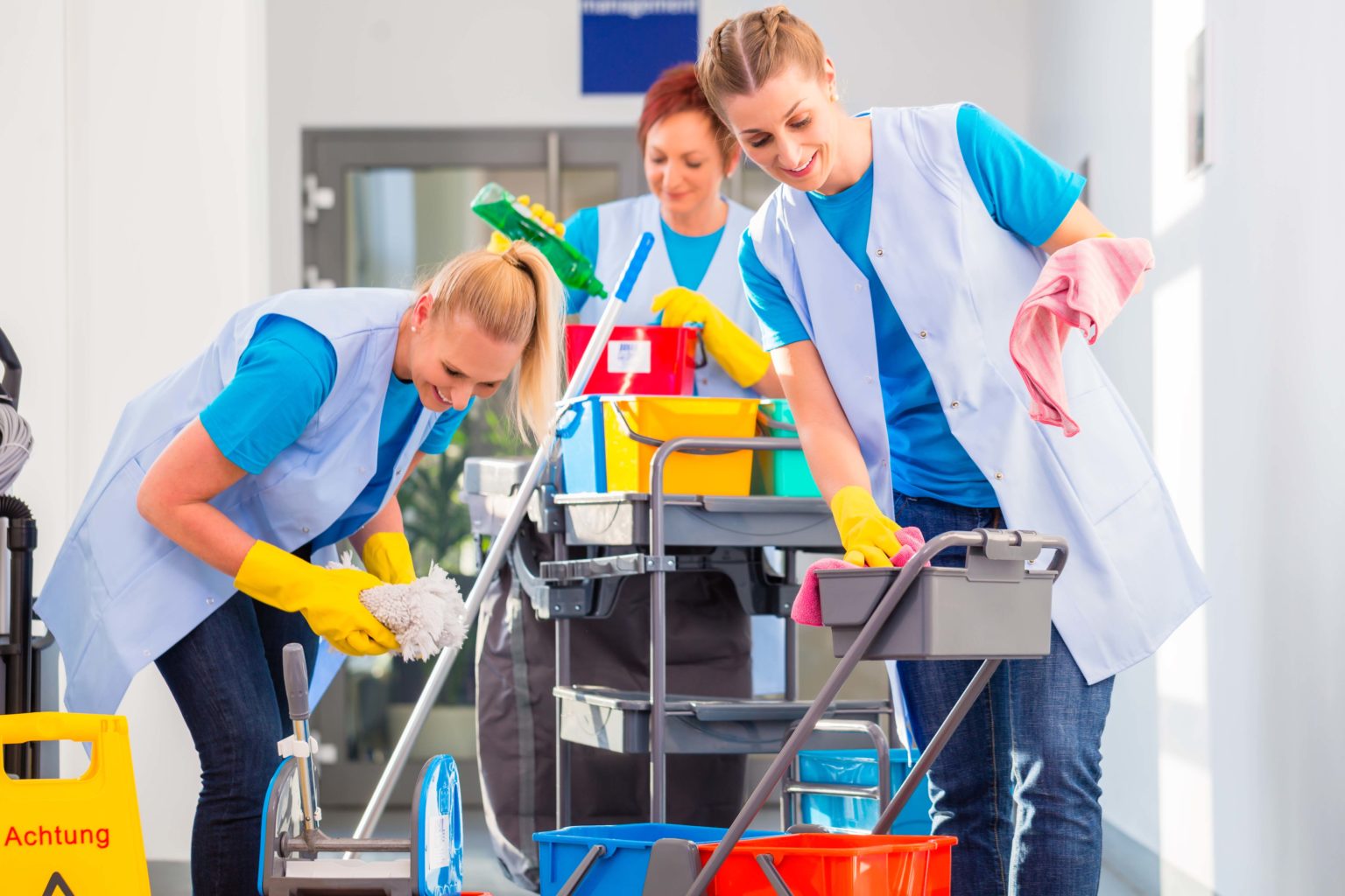 Commercial cleaners doing the job together, three women with trolley working